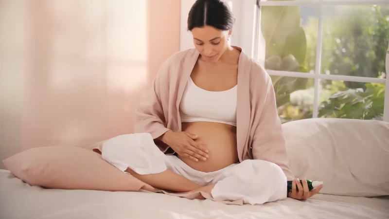 Trudna žena masira stomak na krevetu